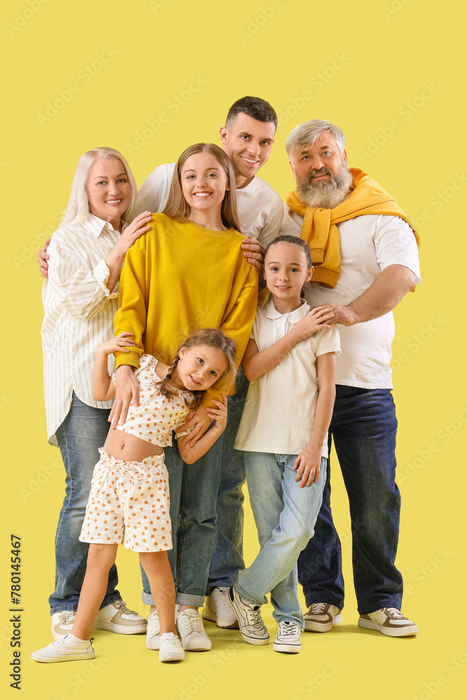 Wall mural Big family hugging on yellow background