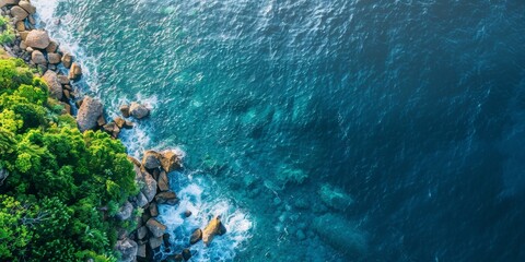 An aerial view capturing the vast ocean with scattered rocks and lush green trees along the shore - Powered by Adobe