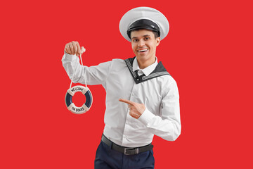 Young sailor with small ring buoy on red background