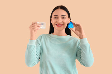 Beautiful young happy woman with dental floss and mini toothbrushes on beige background
