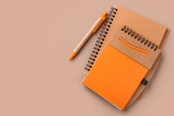 Orange notebooks and pen on brown background