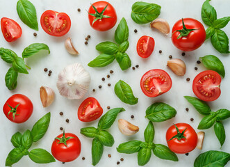 Red cherry tomatoes and basil and garlic on white marble background, top view