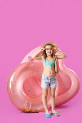 Cute little girl with inflatable ring and mattress on purple background