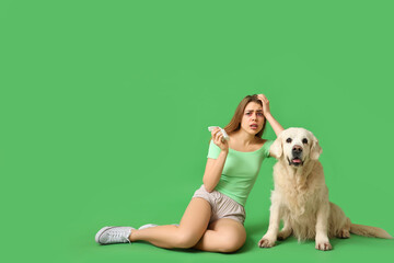 Young woman suffering from pet allergy with labrador dog on green background