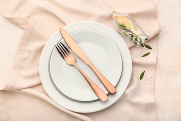 Stylish table setting with leaves in champagne glass on light background
