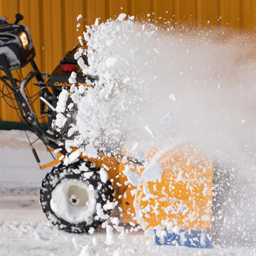 An experienced worker snowblower to efficiently clear snow after winter storm, effectively blows away snow, as shown in image with selective focus and motion blur. Kamchatka, Russia - March 19, 2024