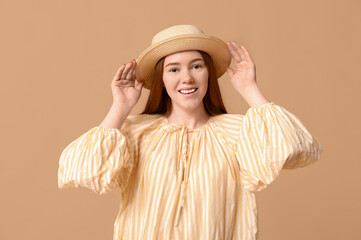 Stylish young girl in dress and hat on beige background