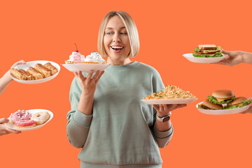 Beautiful woman and hands with unhealthy food on orange background. Overeating concept