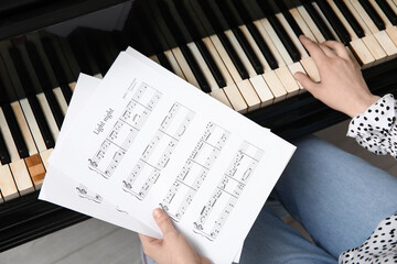 Woman with music sheets playing piano, closeup
