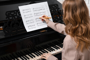 Woman playing piano and writing notes, closeup