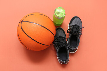Trainers, sport bottle and basketball on orange background