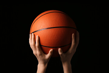 Young basketball player with ball on black background