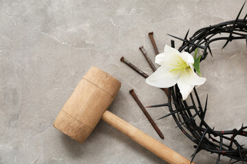 Crown of thorns, lily, hammer and nails on grey background
