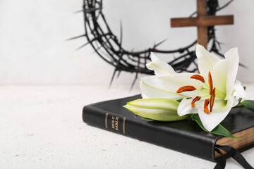 Holy Bible with lilies on grunge table near white wall