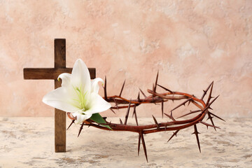 Crown of thorns, white lily and wooden cross on light background