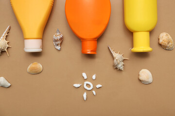 Sun made of cream with bottles of sunscreen and seashells on brown background