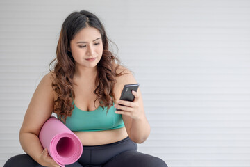 portrait of chubby woman using mobile phone and yoga mat with copy space