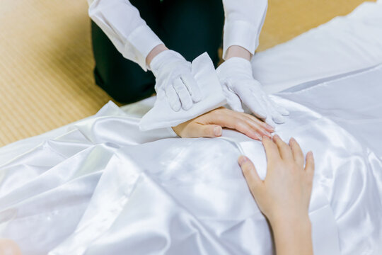 故人の体を拭く湯灌師・納棺師・おくりびと・エンバーマーの日本人女性（エンゼルケア・清拭）
