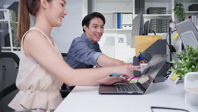 Young asian businessman manager or mentor helping colleague, new employee, teaching intern, explaining online job using laptop computer, talking, having teamwork discussion in office