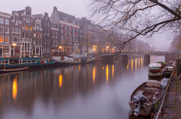Amsterdam canal Singel with typical dutch houses during morning blue hour, Holland, Netherlands.