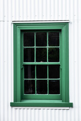 Old green sliding sash window on a white wall