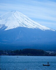 雄大な富士山の下で浮かぶ小さな釣り船　河口湖