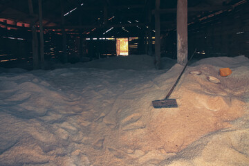 Mounds of harvested salt inside a spacious, dimly lit wooden and run down storage house, a...