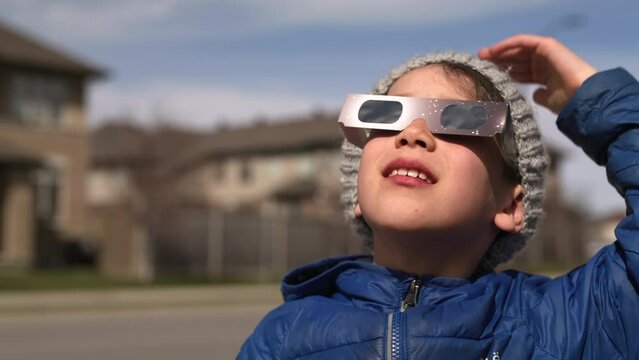 Young boy watching solar eclipse with special glasses very excited