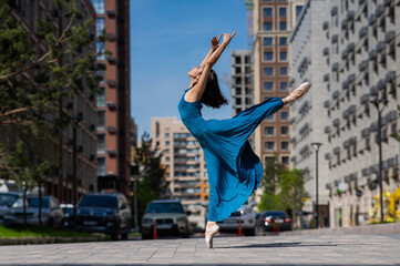 Fototapeta na wymiar Beautiful Asian ballerina in blue dress dancing outdoors. Urban landscape.