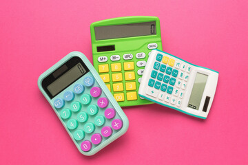 Three calculators lying on top of each other on a red background.