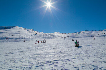 People riding downhill on tubing and sledding in the mountains in winter on a sunny day off - 780211693