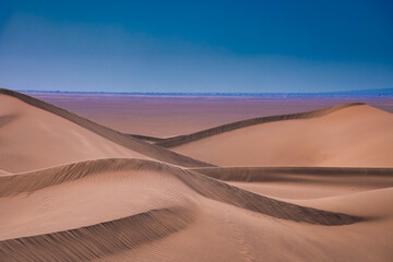 A sand dune of sahara desert at Mhamid el Ghizlane in Morocco telephoto shot - obrazy, fototapety, plakaty