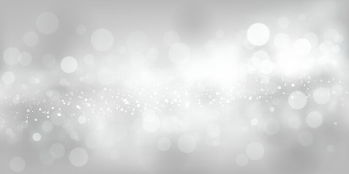 Abstract background in white and gray tones with many shiny sparkles, some of which are in focus and others are blurred, creating a captivating bokeh effect.