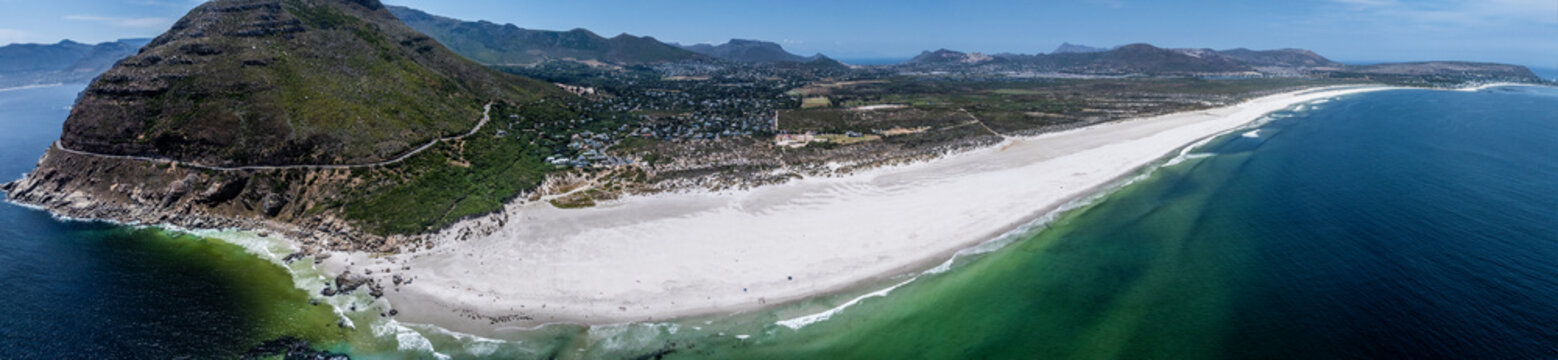 panoramic aerial landscape view the famous, natural very long Noordhoek Beach with white sand beach and Chapman's peak mountain 