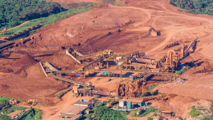 aerial view of a Bauxite Mine with massive equipment and machines, the surrounding earth surface is...