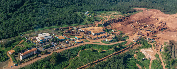 aerial landscape view around a Bauxite mining plant located within a green forest with ocean in the...