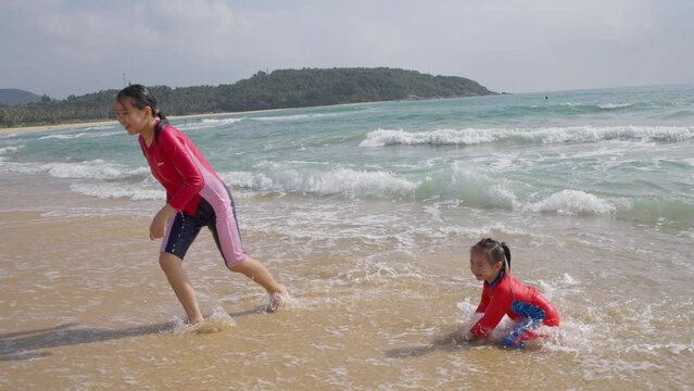 slow motion of two happy kids playing on the Riyue bay at Wanning Hainan China