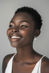 Portrait of happy woman looking upward. Young African woman looking upwards with a joyful expression, in a white top with minimalistic earrings