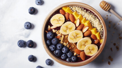 Fototapeta na wymiar Acai bowl topped with banana slices, blueberries, almonds, and granola on a marbled surface.