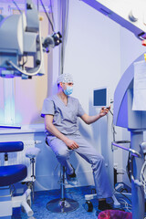An oculist doctor sits on the background of a modern microscope for vision testing in the office....