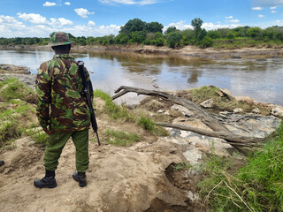 African soldier are walking along river bank, tracking wild animals.