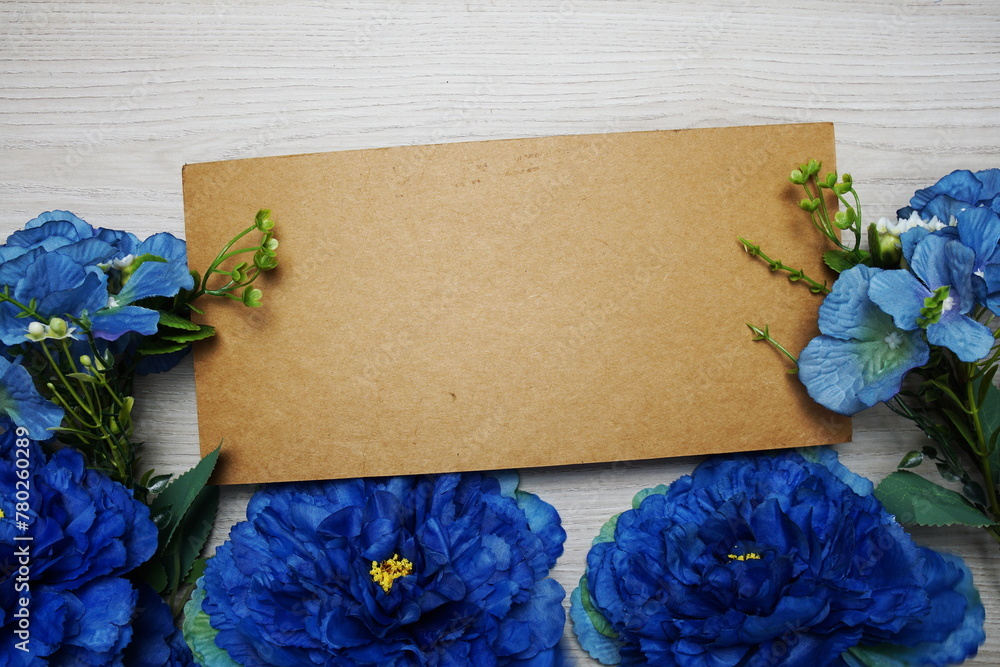 Poster beautiful flowers with invitation or greeting card mockup with space for text message flat lay on wo