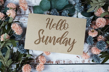 Happy Sunday text message on paper card with flowers border frame on wooden background