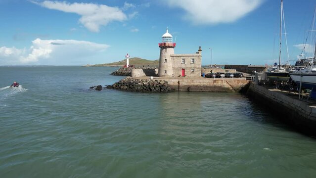 Howth Ireland low drone lighthouse flyover afternoon bright sun crystal blue water
