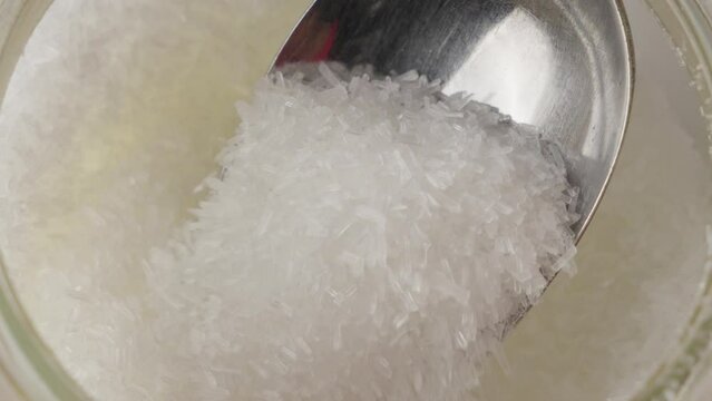 Refined white MSG (monosodium glutamate) covered by steel spoon