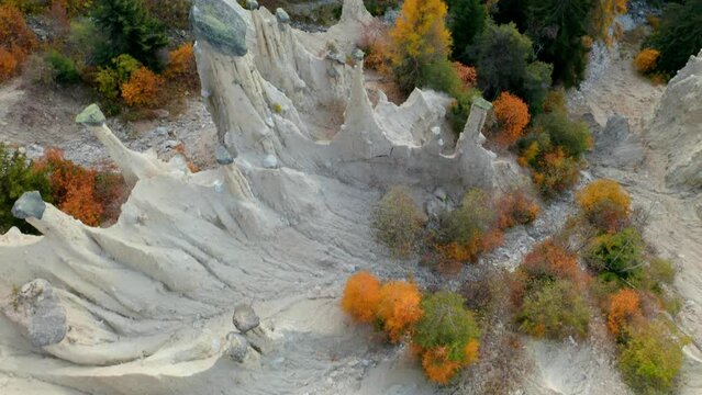 4k drone flying over footage (Ultra High Definition) of Earth pyramids of Platten - Spiky sand towers formed by water erosion and accessed by a woodland trail dotted with sculpture.
