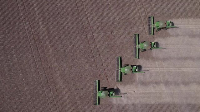 Several harvesters unloading soybeans after harvest. Real farm in the interior of Mato Grosso in Brazil. Aerial image. Side-by-side harvesters