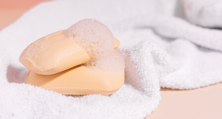 Two soap bars of soap on a white towel on a beige background.