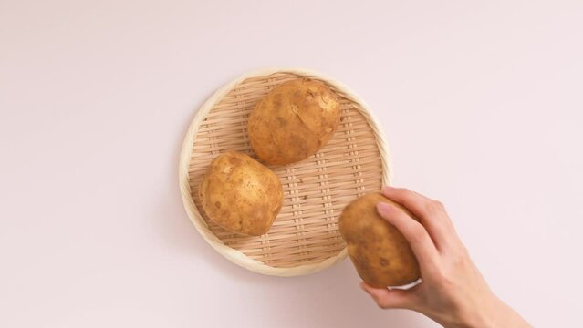 A woman take the potatoes on white background.  白背景上にあるジャガイモを取る女性