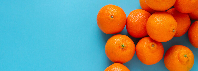 Fresh orange fruits on right side of light blue background. Vibrant horizontal banner of citrus...